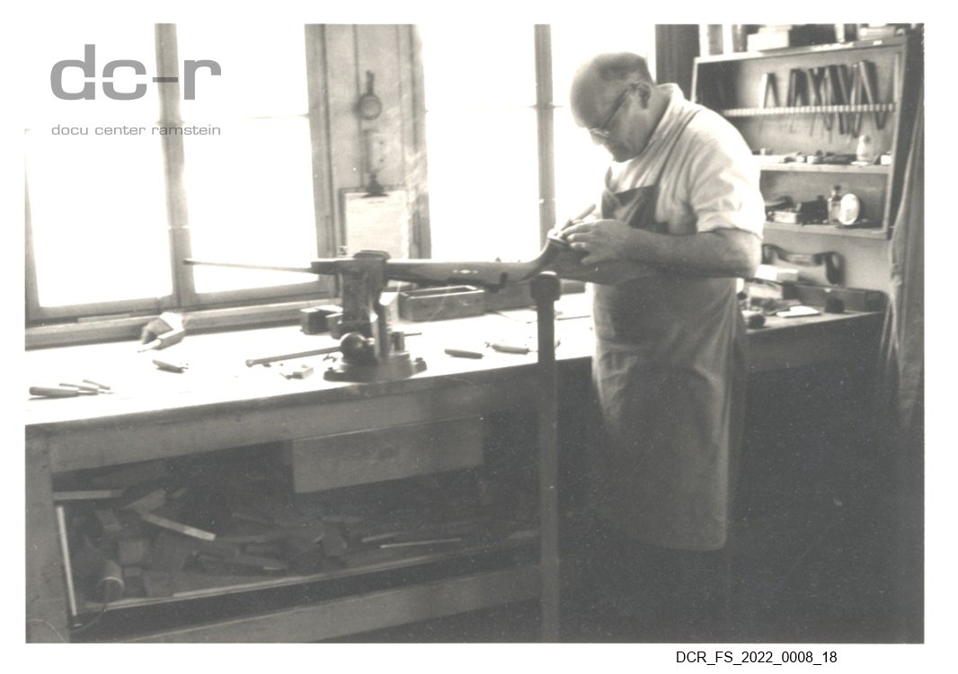 Schwarzweißfoto, Portraitaufnahme von Josef Fuchs bei der Arbeit an einem Gewehrkolben ("dc-r" docu center ramstein RR-F)