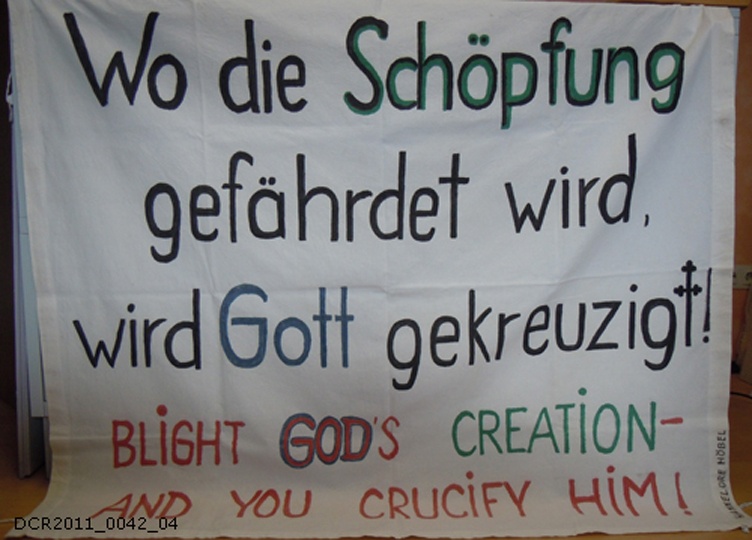 Demonstrationsbanner "Wo die Schöpfung gefährdet wird, wird Gott gekreuzigt" ("dc-r" docu center ramstein CC BY-NC-SA)