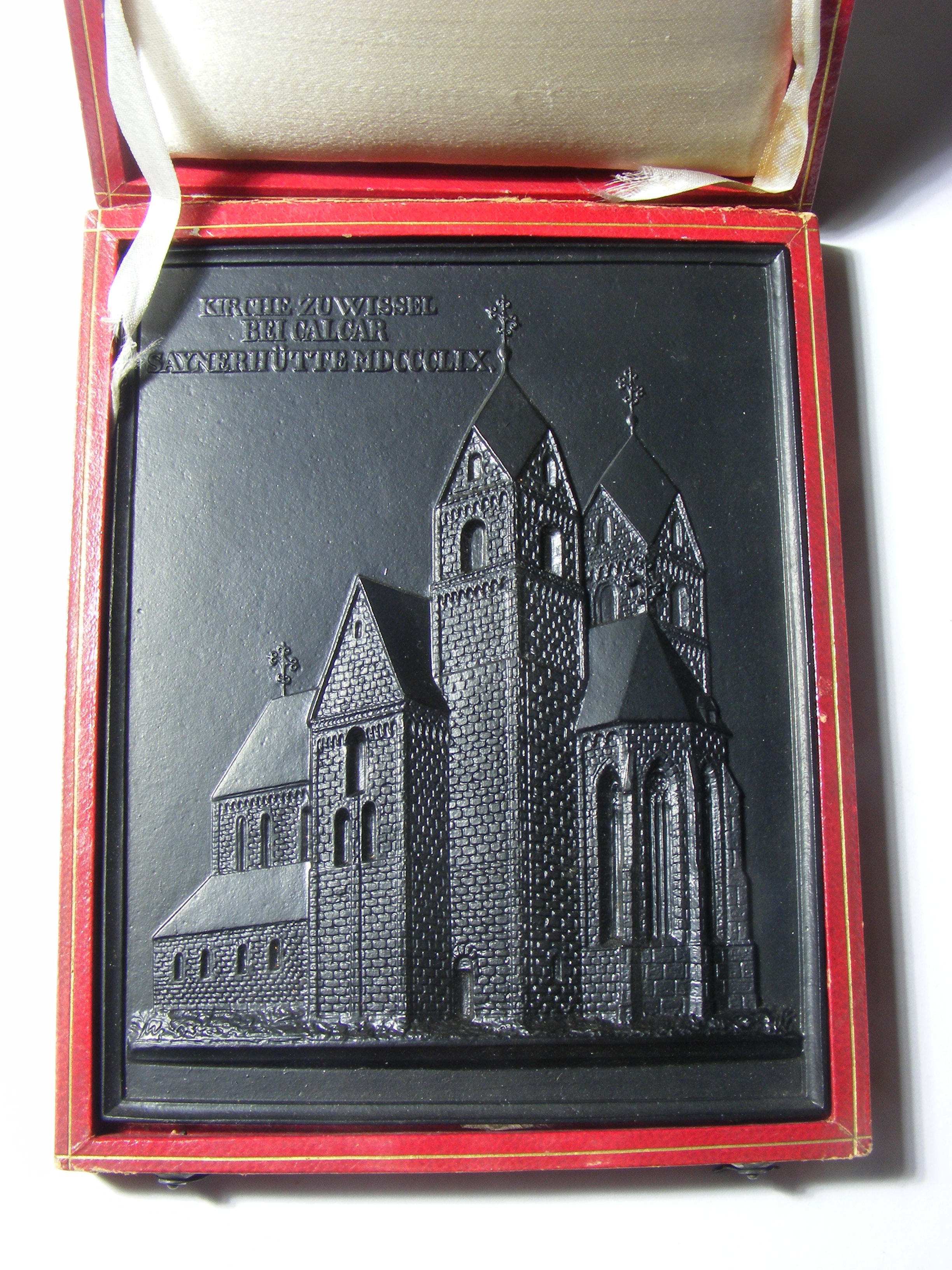 Sayner Neujahrsplakette 1859, "Kirche zu Wissel bei Calcar", in rotem Etui (Seide, Leder, Karton), mit Beschreibung des Baudenkmals (Papier) (Rheinisches Eisenkunstguss-Museum CC BY-NC-SA)