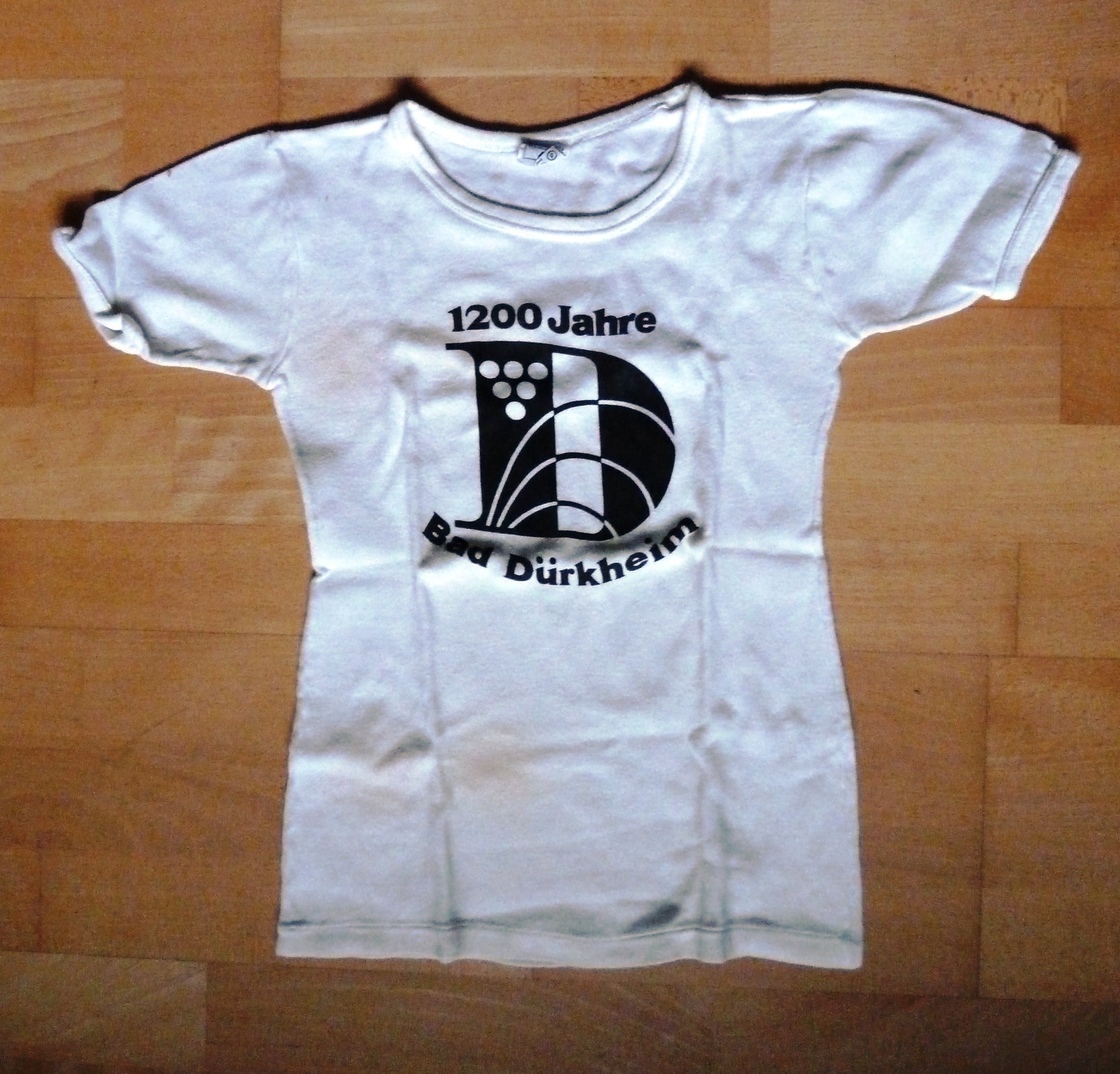 T-Shirt aus Baumwolle; weiß mit schwarzer Aufschrift: "1200 Jahre Bad Dürkheim"; 20. Jh. (Stadtmuseum Bad Dürkheim, Museumsgesellschaft Bad Dürkheim e.V. CC BY-NC-SA)