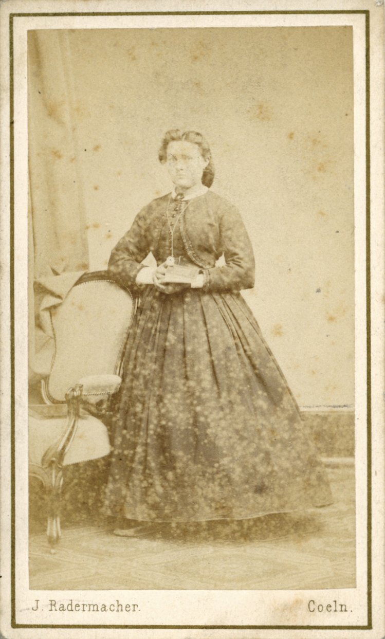 Fotografie einer stehenden Dame neben einem Sessel (Freilichtmuseum Roscheider Hof CC0)