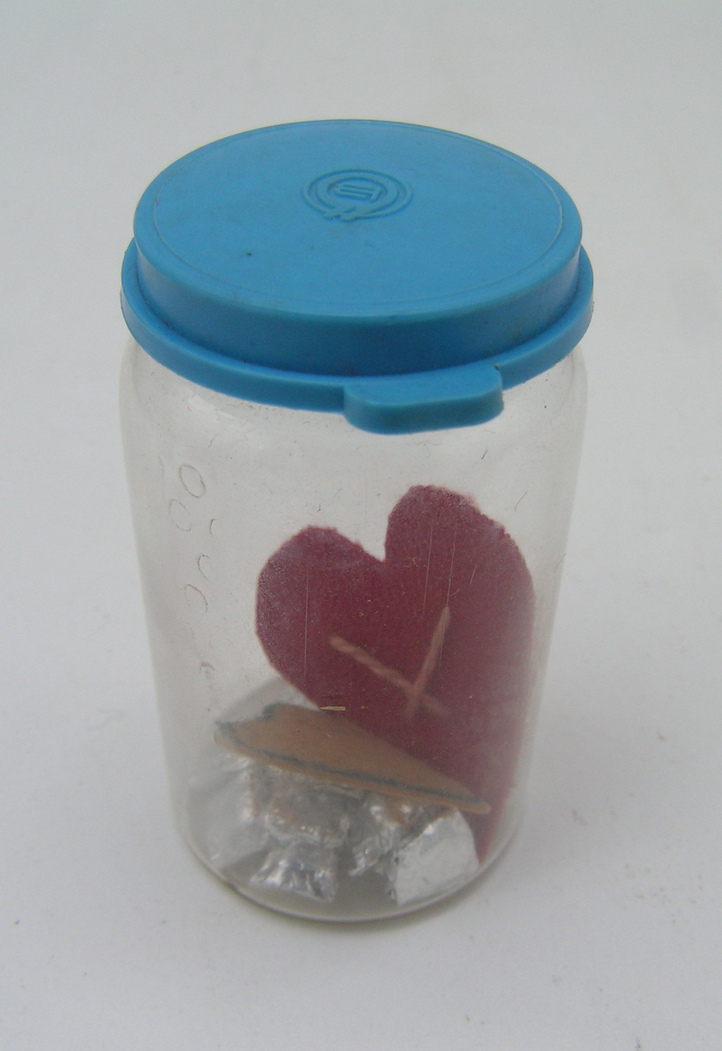 Glas mit 12 Wachsstücken in Alufolie und zwei ausgeschnitte Herzen aus Leder (Freilichtmuseum Roscheider Hof CC0)
