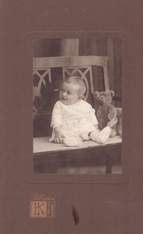 Foto Kleinkind mit Teddy auf einer Bank sitzend. (Freilichtmuseum Roscheider Hof CC0)