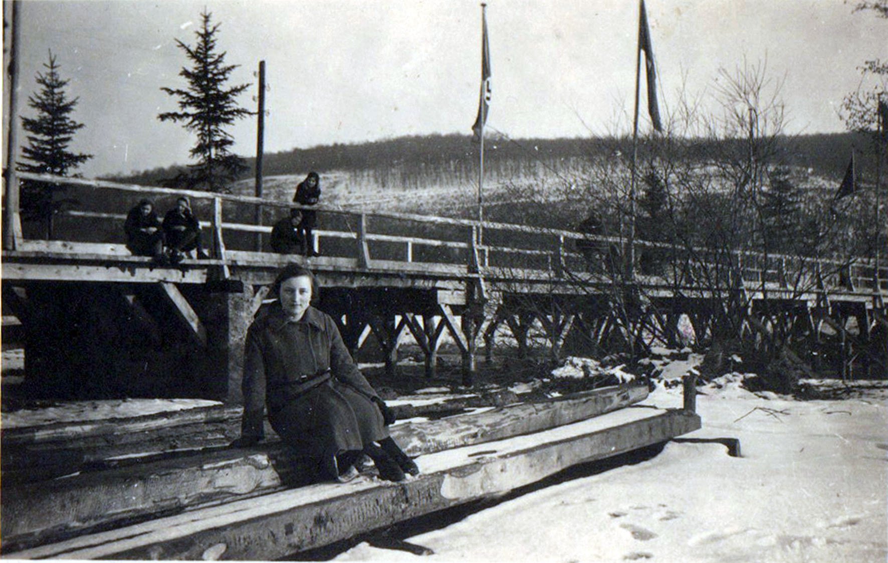 Junge Frau sitzt vor der 1940 erstellten hölzernen Ahrbrücke (Heimatarchiv Bad Bodendorf CC BY-NC-SA)