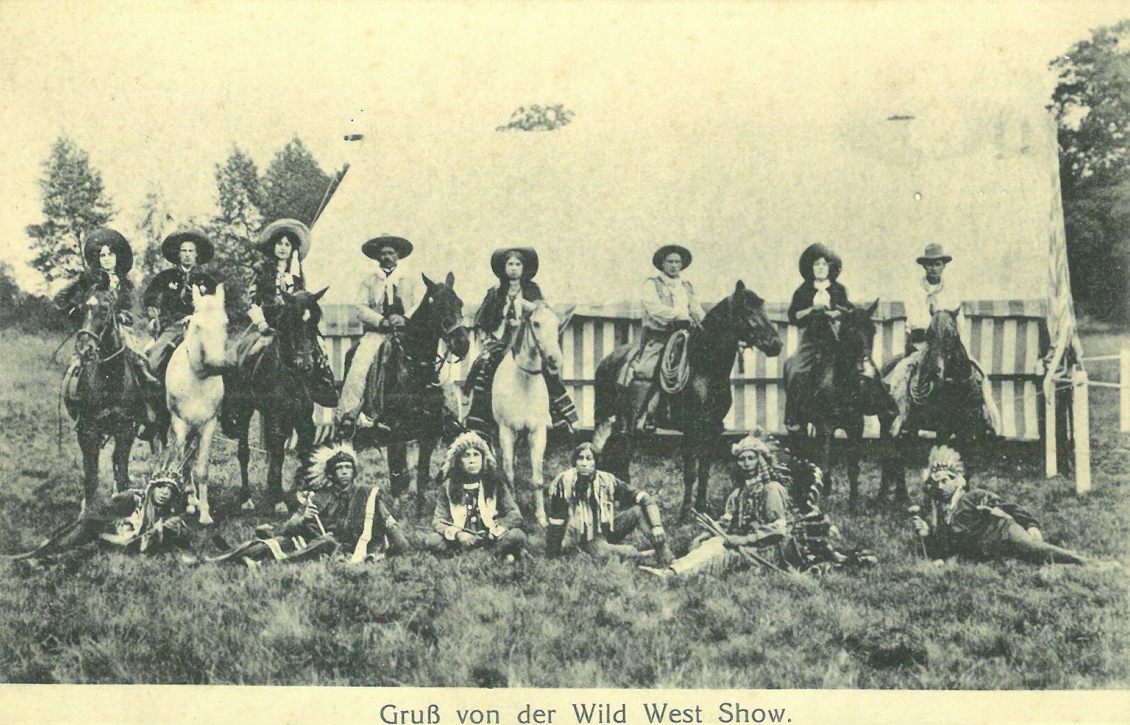 Wild West Show der Deer Family; Gruppenbild Cowboy-Darsteller zu Pferd und Darsteller Indigene sitzend (Karl-May-Museum gGmbH RR-R)