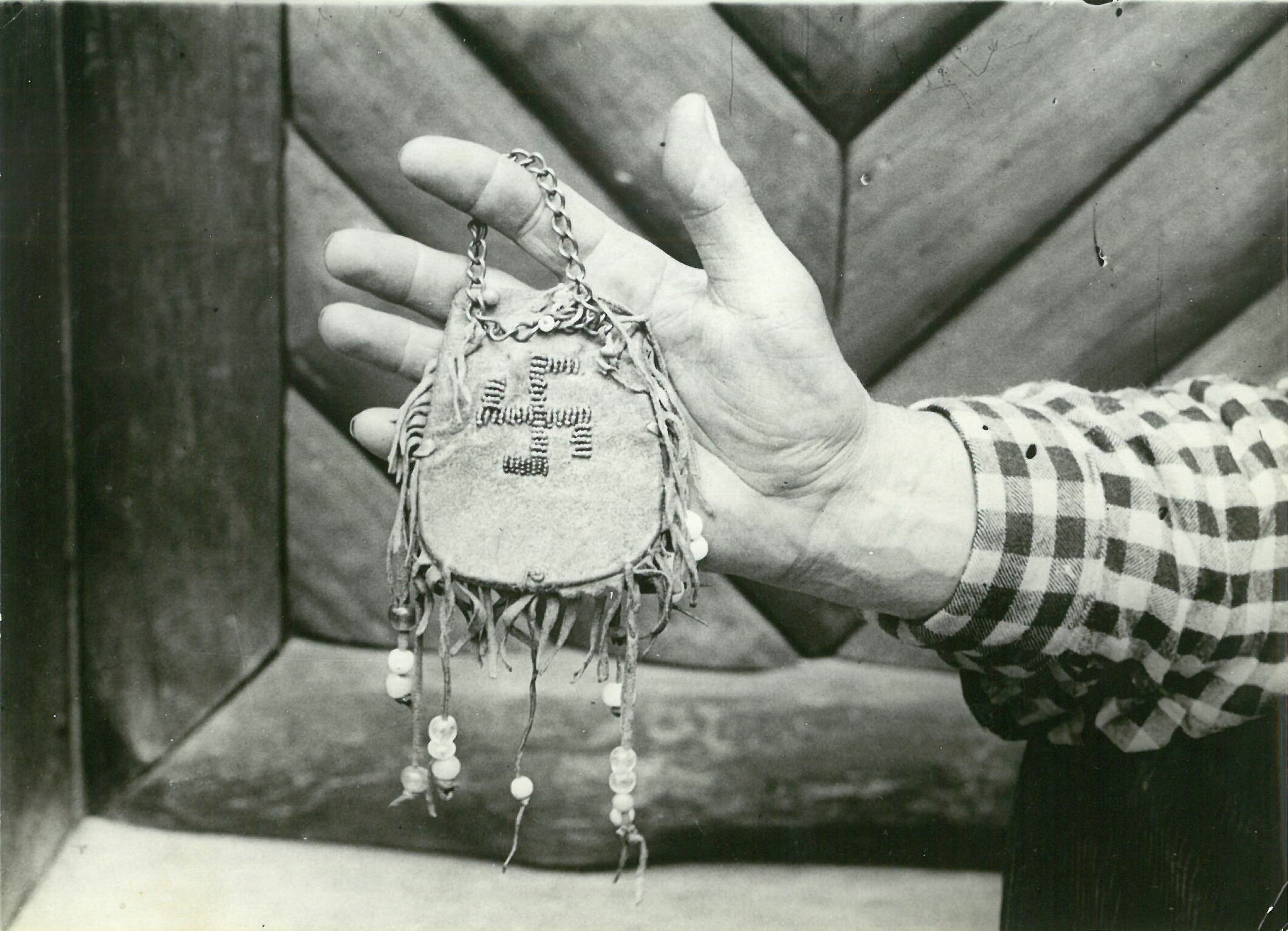 Patty Frank zeigt Lederbeutel mit Perlenstickerei in Form einer Swastika; vor Villa Bärenfett (Karl-May-Museum gGmbH RR-R)
