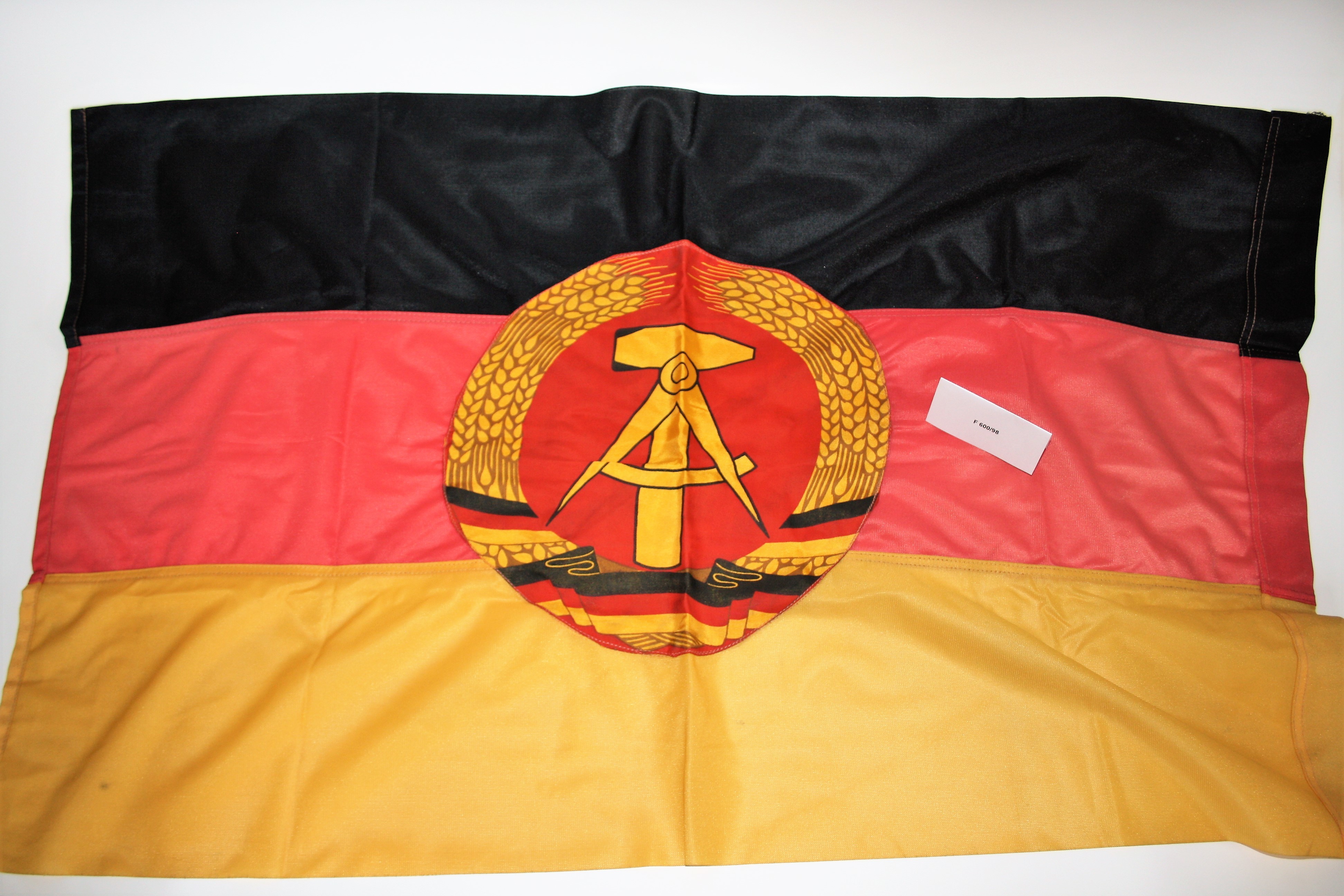 Schwarz- rot- gelbe Dederonfahne mit DDR- Emblem (Industrie- und Filmmuseum Wolfen CC BY-NC-SA)