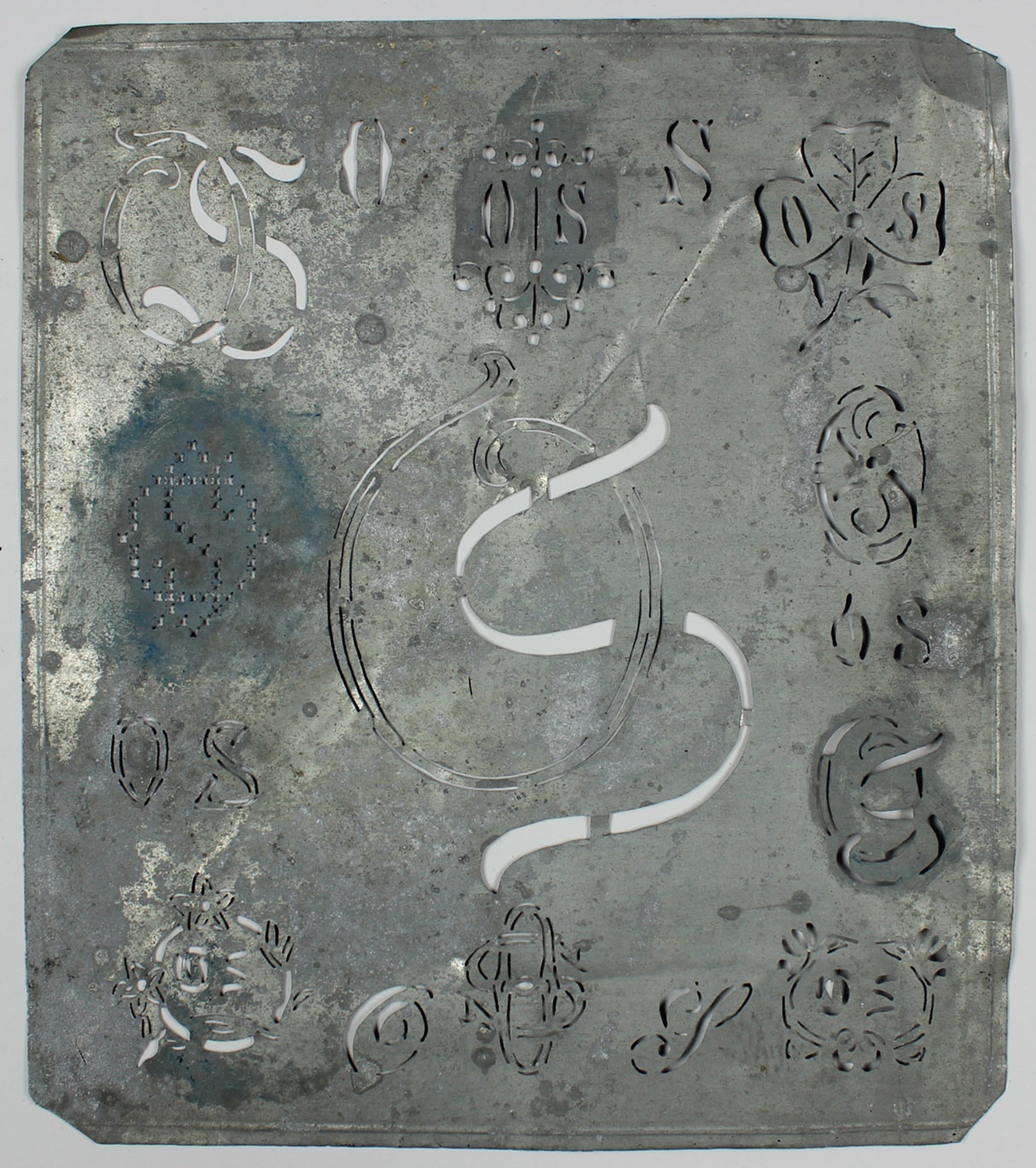 Stickmusterschablone, Blech, verschiedene Blumen- und Buchstabenmotive, in der Mitte "OS" (Museum Wolmirstedt RR-F)