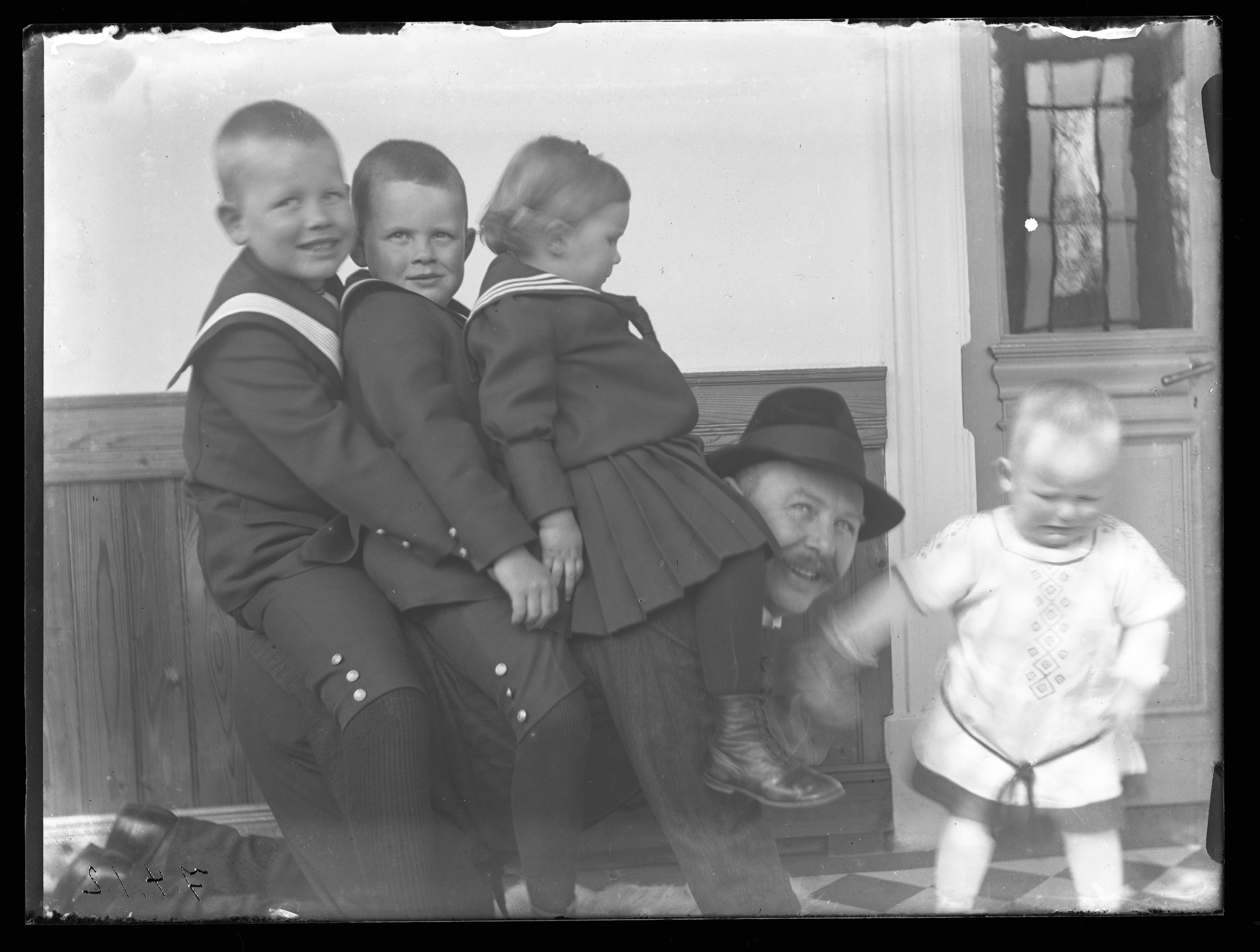 Glasplattennegativ, Carl Bauer mit seinen Kindern spielend, auf der Veranda der Villa Bauer (Seminar für Kulturanthropologie des Textilen an der Technischen Universität Dortmund CC BY-NC-SA)